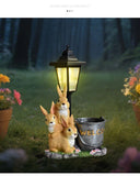 Solar Simulation Rabbit Ornament, charges by day and lights up automatically at night, three rabbits cluster around a street lamp with "WELCOME" bucket, warmly decorates courtyard and balcony, eco-friendly and healing./Resin flowerpot rabbit