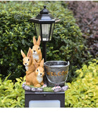 Solar Simulation Rabbit Ornament, charges by day and lights up automatically at night, three rabbits cluster around a street lamp with "WELCOME" bucket, warmly decorates courtyard and balcony, eco-friendly and healing./Resin flowerpot rabbit